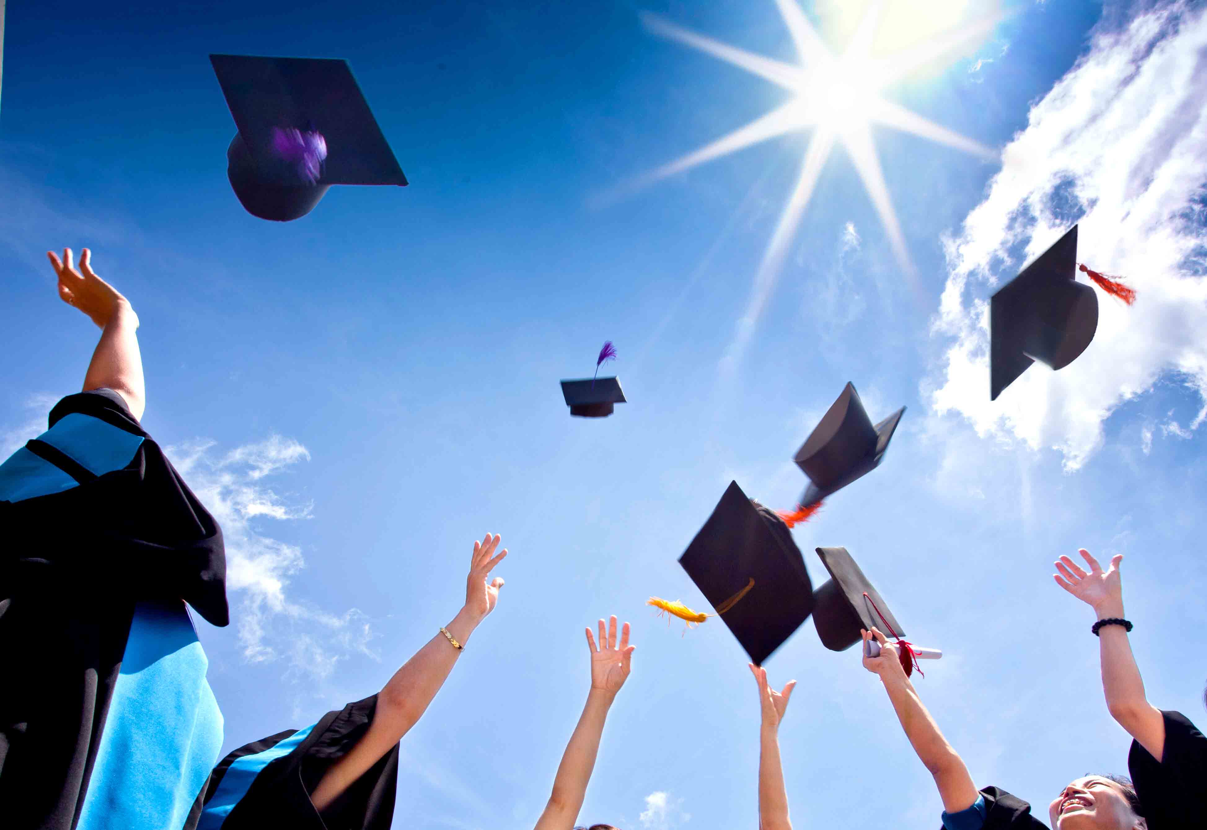 Students with congratulations throwing graduation hats in the air celebrating